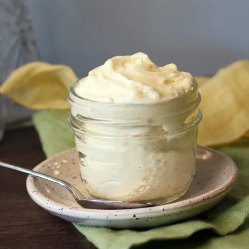 Lemon Mascarpone Cream swirled in a small jar with a spoon.