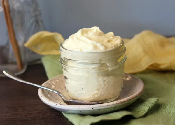 Lemon Mascarpone Cream swirled in a small jar with a spoon.
