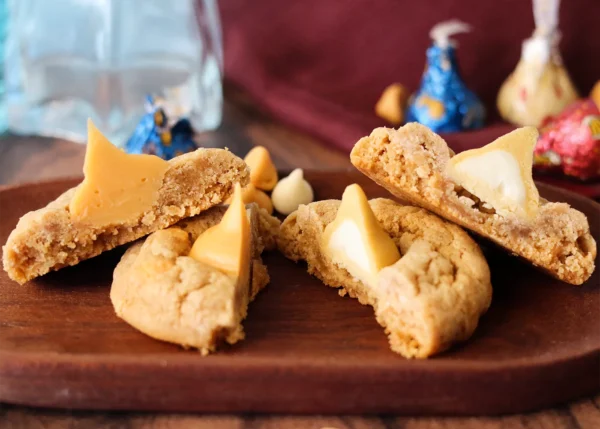 Two Butterbeer blossom cookies cut open to show the cross section when ganache is used versus Butterbeer Kiss in the center.