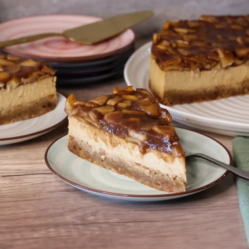 Caramel Apple Blondie Cheesecake slices on dessert plates with full cake in the background.