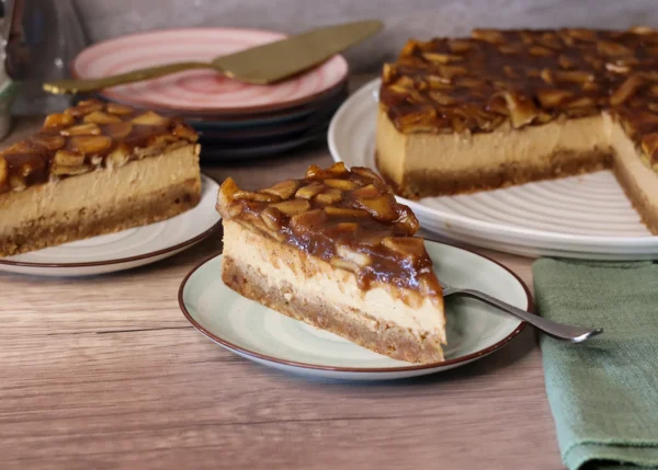 Caramel Apple Blondie Cheesecake slices on dessert plates with full cake in the background.