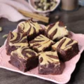 Dirty Chai Cheesecake Brownies arranged on a square pink plate and showcasing the cheesecake swirl.